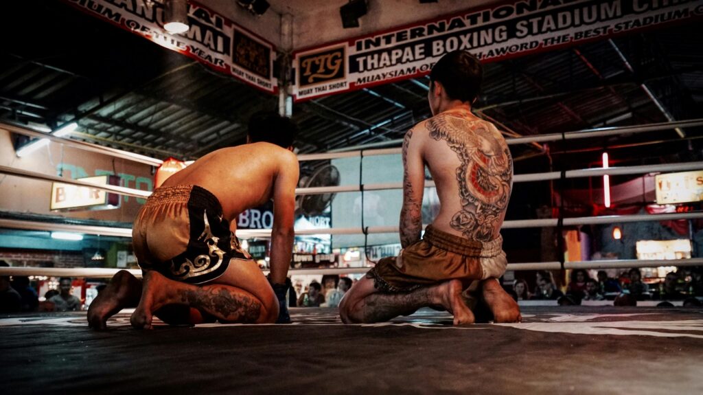 pexels-photo-238636-238636 Two tattooed Muay Thai fighters kneeling in a boxing ring at Thapae Boxing Stadium.