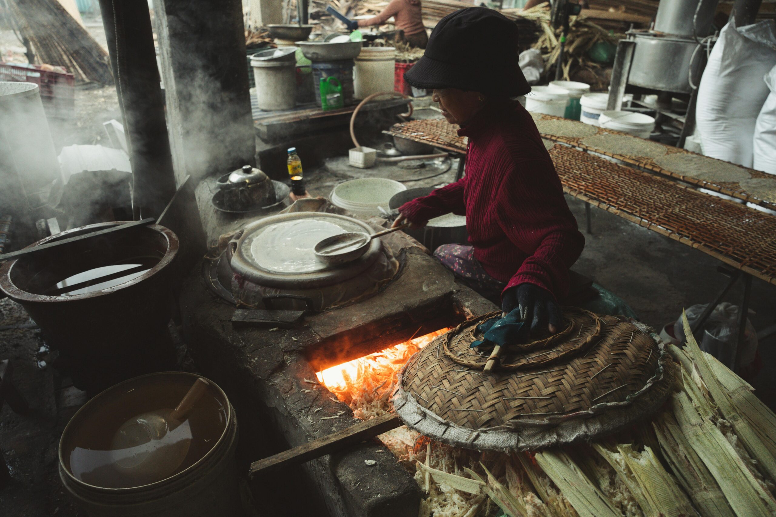 Artisan cooking with traditional methods over an open flame in a rustic kitchen.
